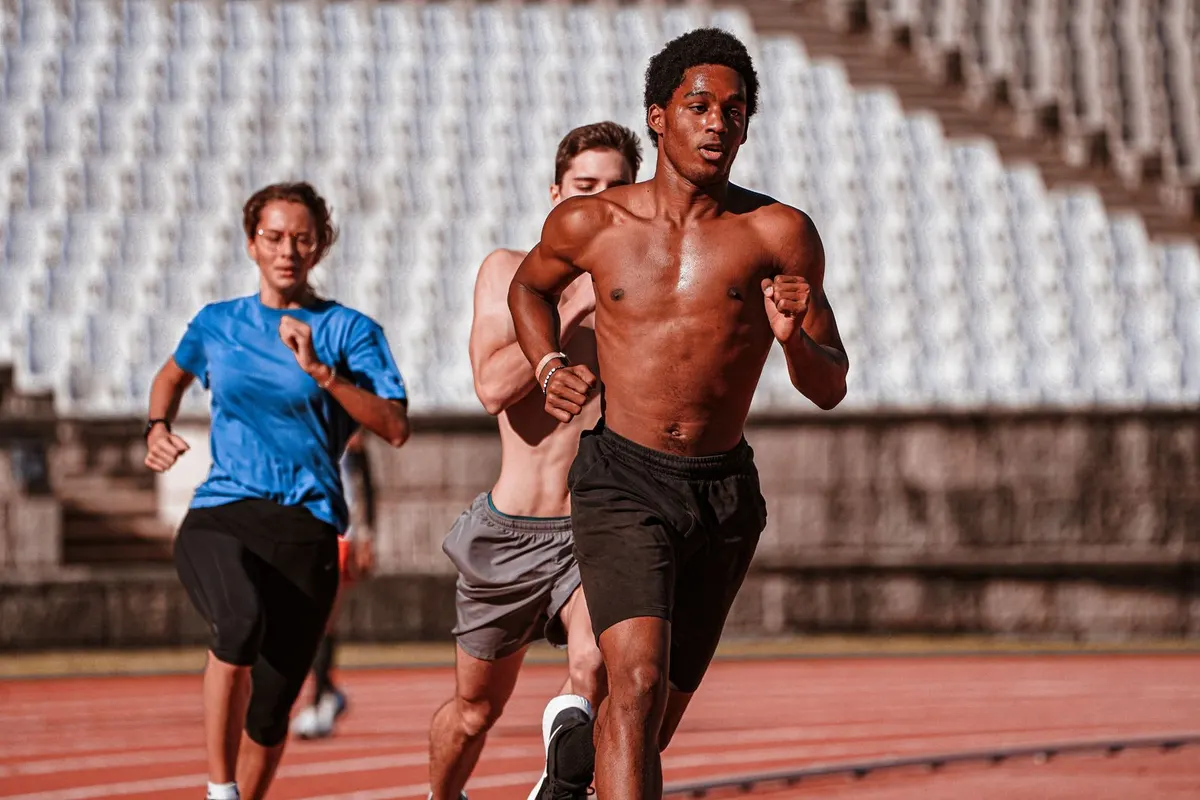 Grupo de personas corriendo en una pista de atletismo durante un entrenamiento