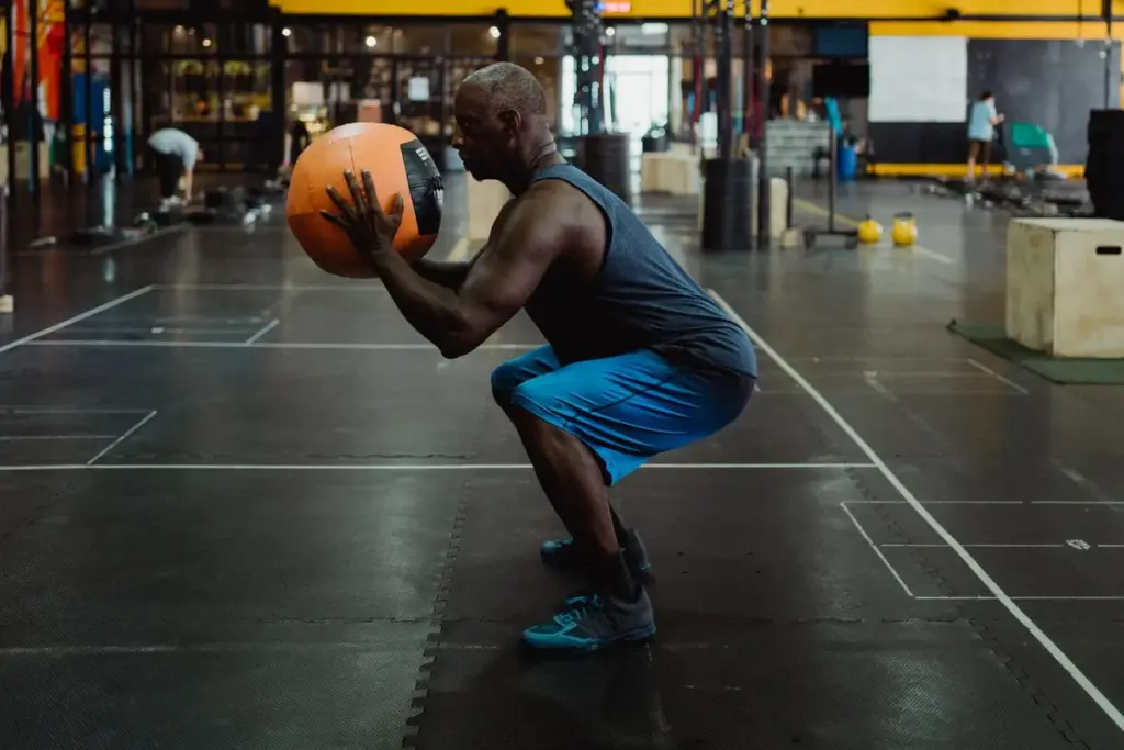 Hombre entrenando con un balón medicinal en un gimnasio