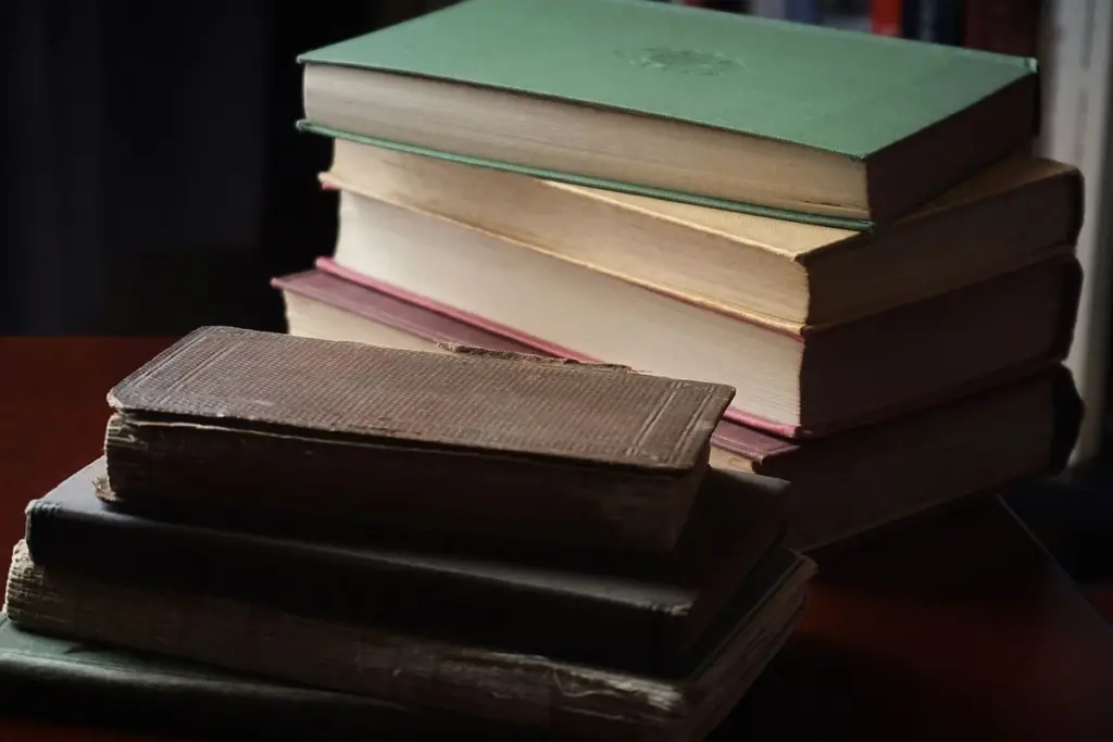 Libros de tapa dura apilados sobre una mesa de estudio