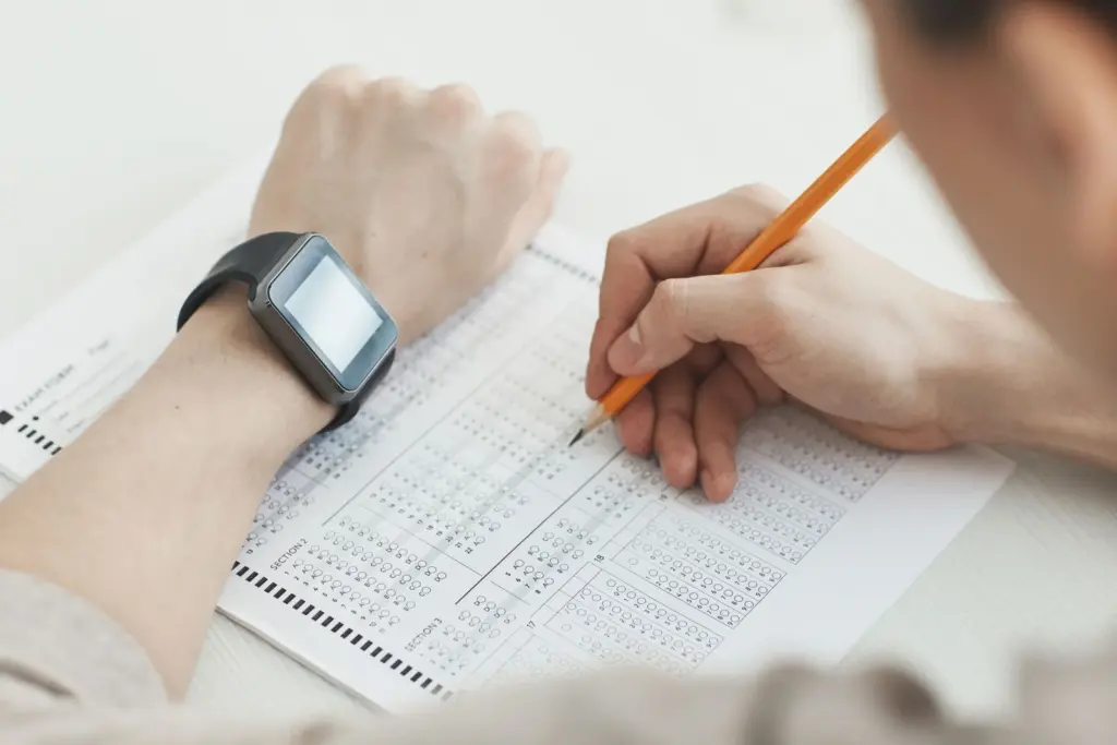 Persona rellenando una hoja de respuestas tipo test con un reloj en la muñeca