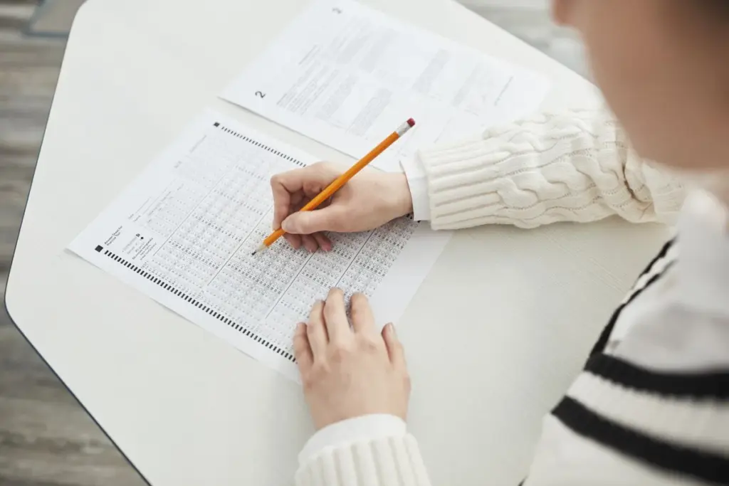 Mano marcando respuestas con lápiz en la hoja de un examen tipo test