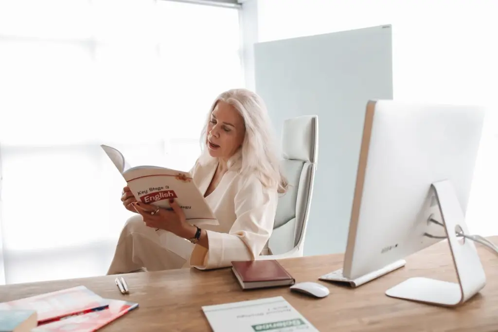 Mujer estudiando con un libro de inglés en su escritorio