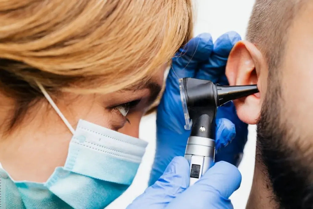 Profesional sanitaria revisando el oído de un paciente con un otoscopio